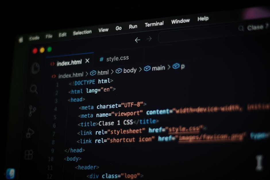 A close-up view of a person's hands operating a laptop computer placed on a dark surface. The screen displays lines of computer code in a dark theme, with various colors highlighting syntax. The perso